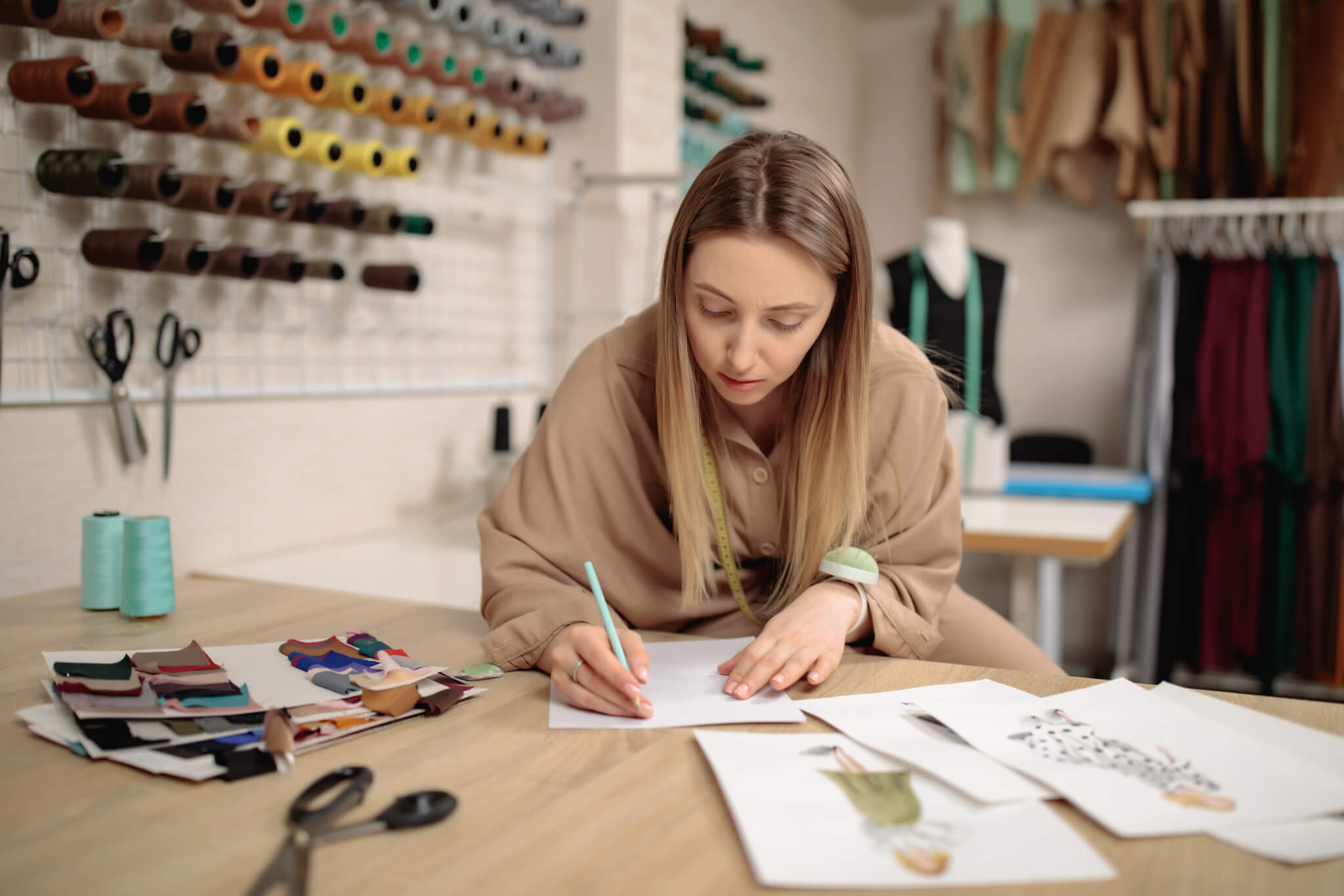 woman fashion designer draws sketches. attractive young female dressmaker sketching in studio