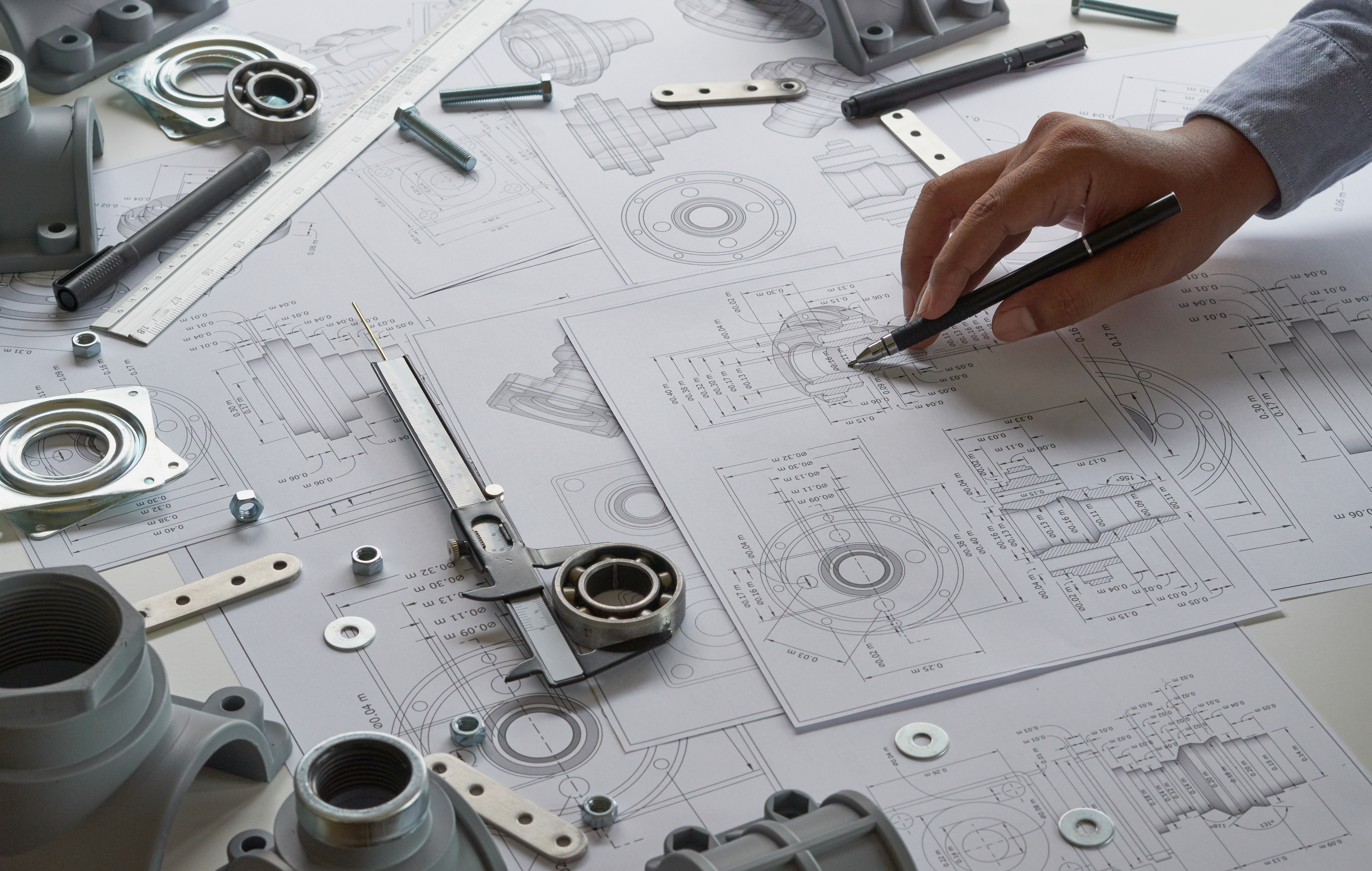 Engineer technician designing drawings mechanicalÂ parts engineering Enginemanufacturing factory Industry Industrial work project blueprints measuring bearings caliper tools