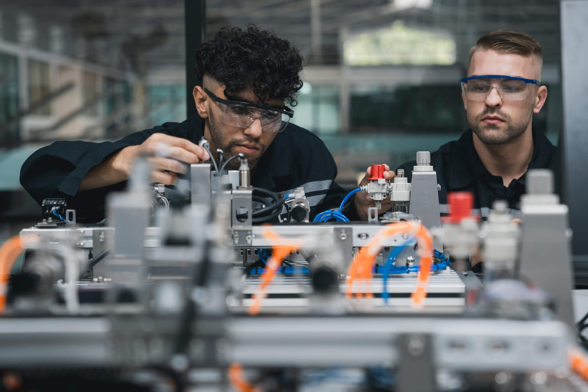 Student engineer Assembling Robotic Arm with computer in Technology Workshop. Service Engineer Holding Robot Controller and Checking Robotic Arm Welding Hardware.