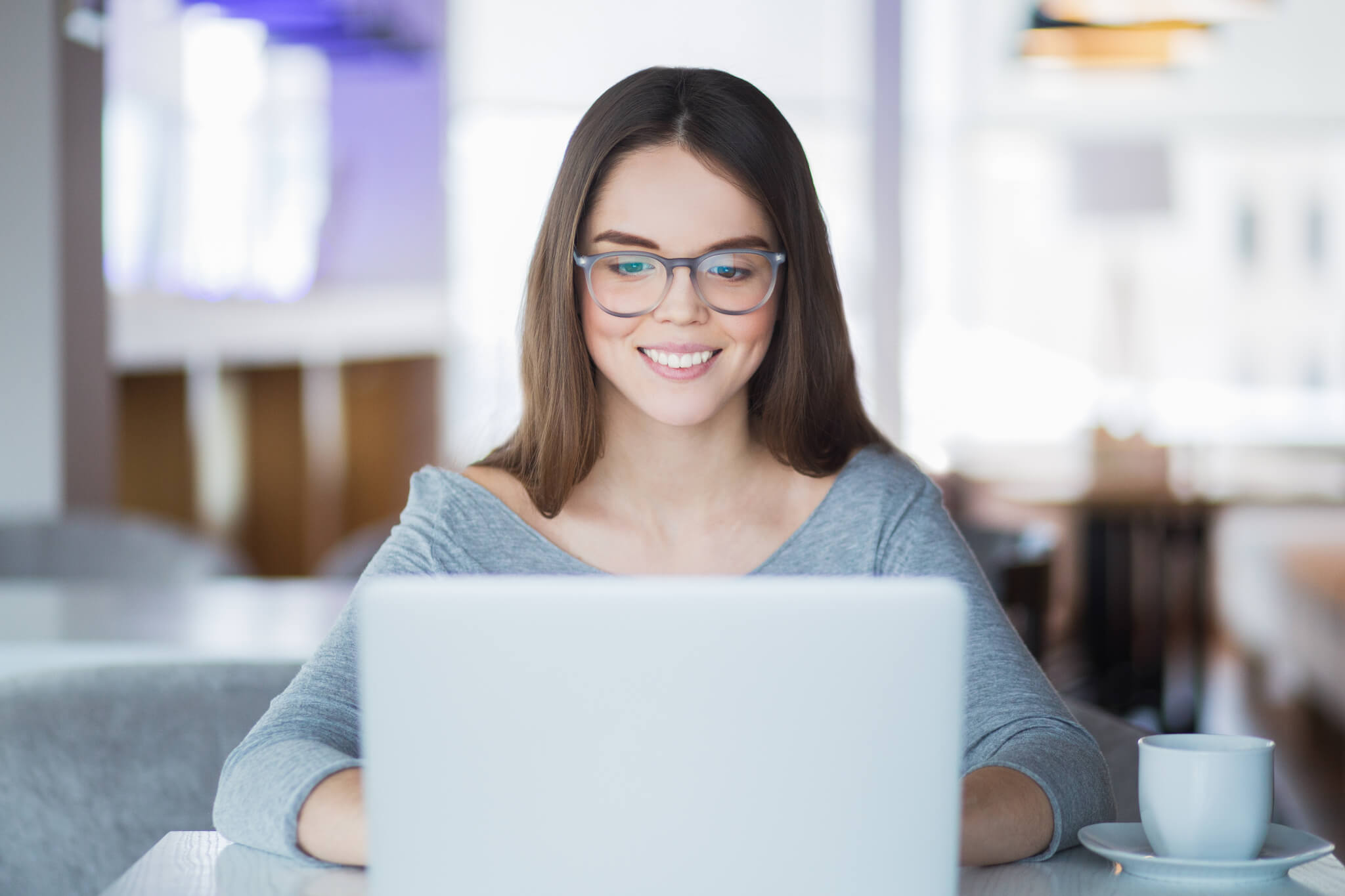 Portrait of cheerful student using laptop in cafe