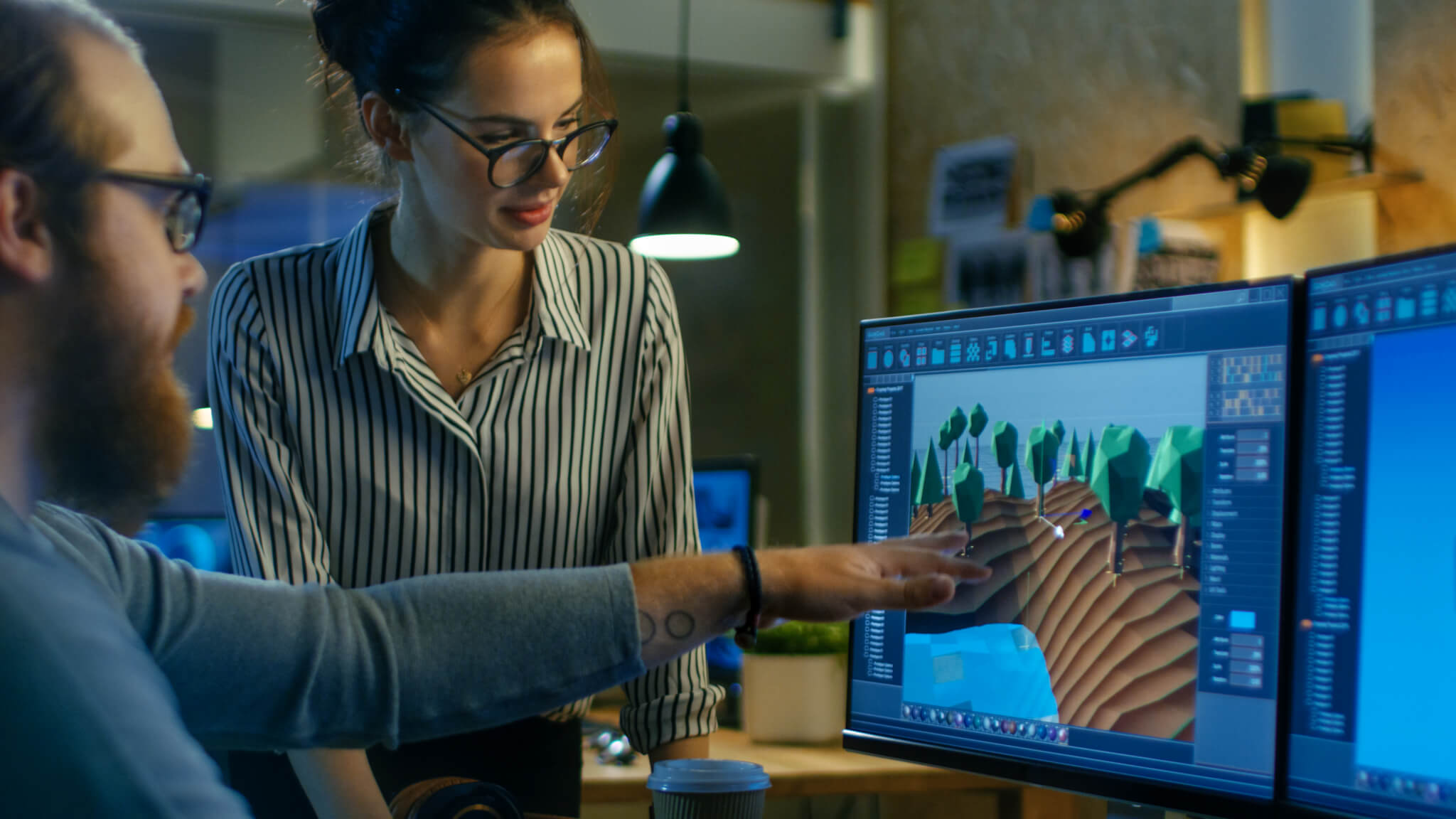 Male Game Developer Talks with Artistic Female Level Designer. Two Displays Show Totally Original Game. They Work in a Creative Office Loft.