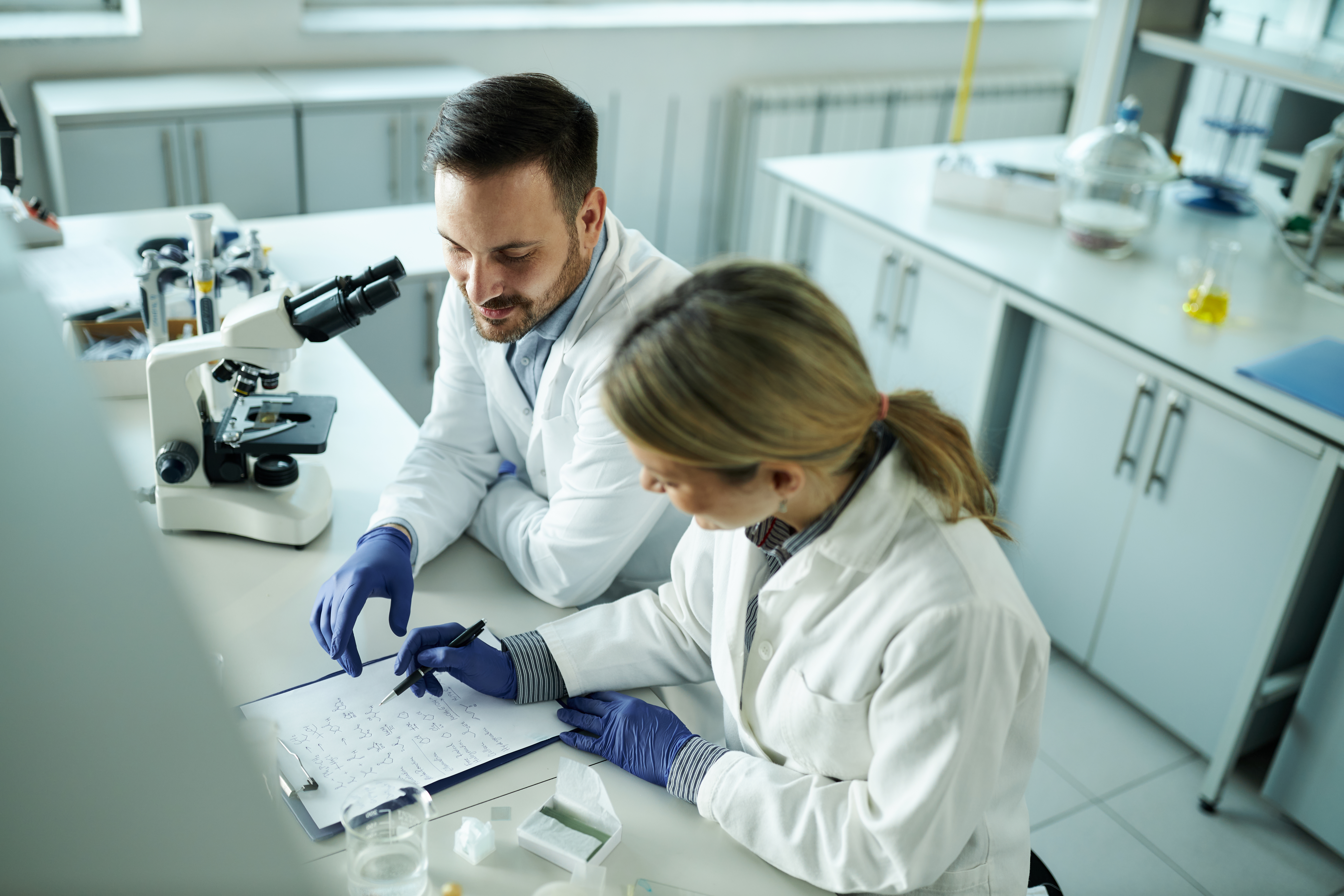 Concentrated scientists working on chemical formula in laboratory.