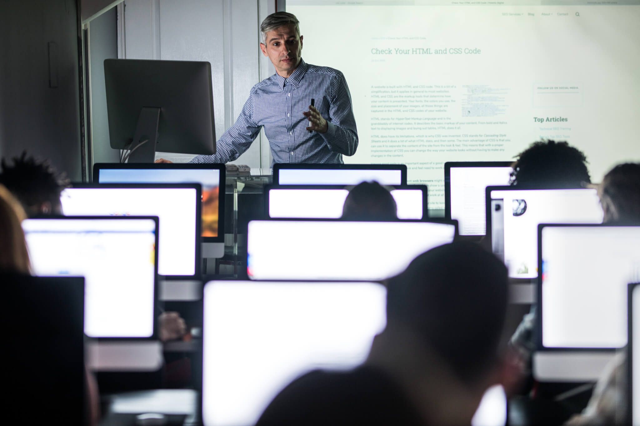 Mid adult teacher giving a lesson in computer lab.