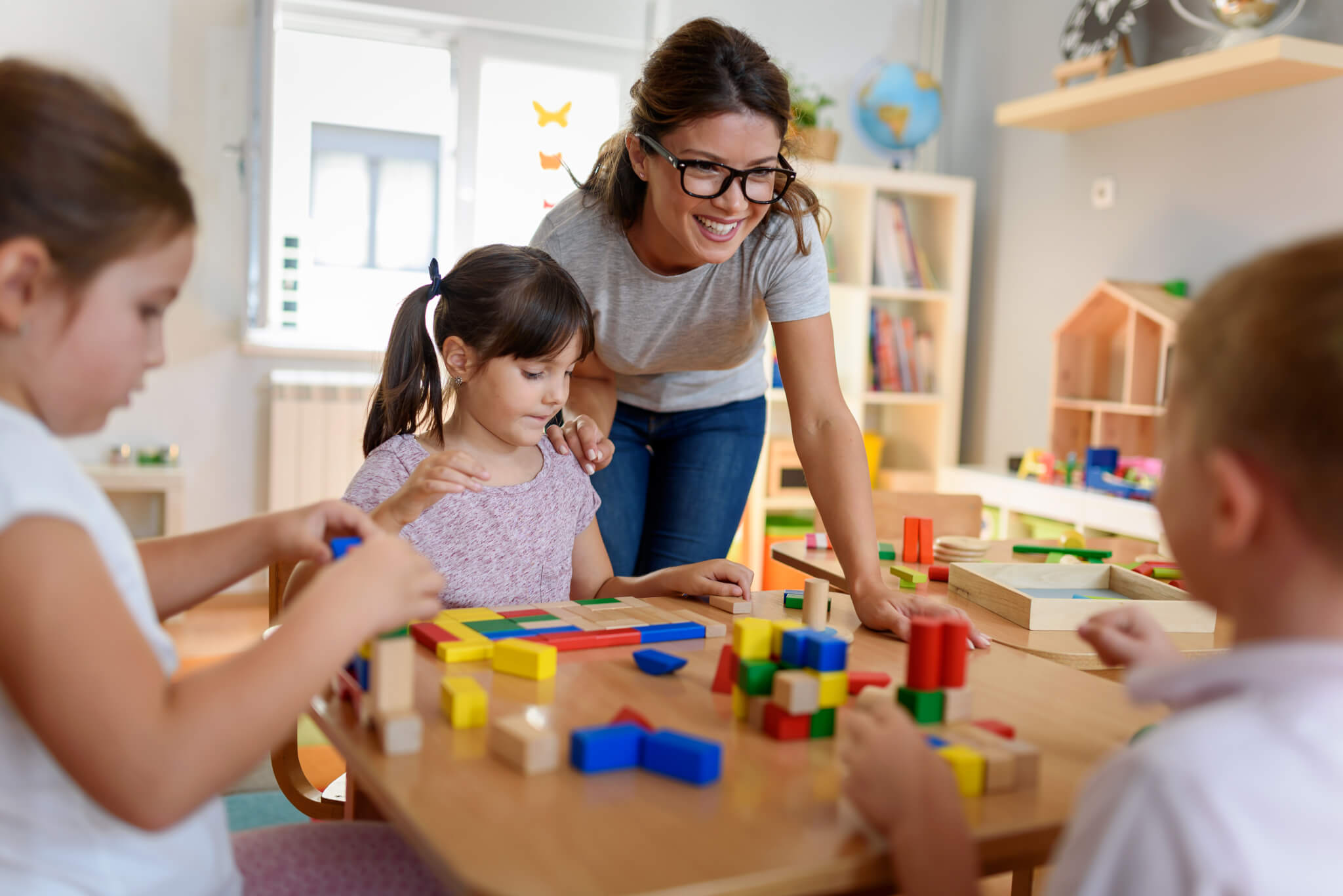 Preschool teacher with children playing with didactic toys