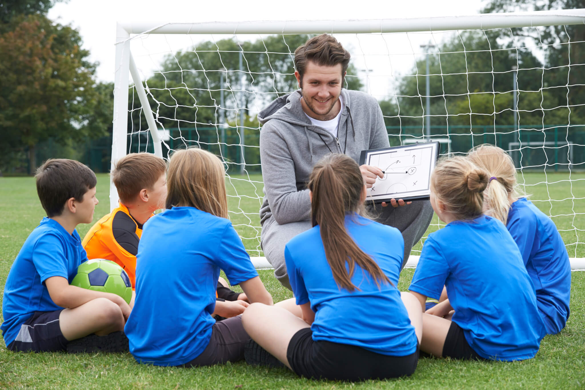 Coach Giving Team Talk To Elementary School Soccer Team