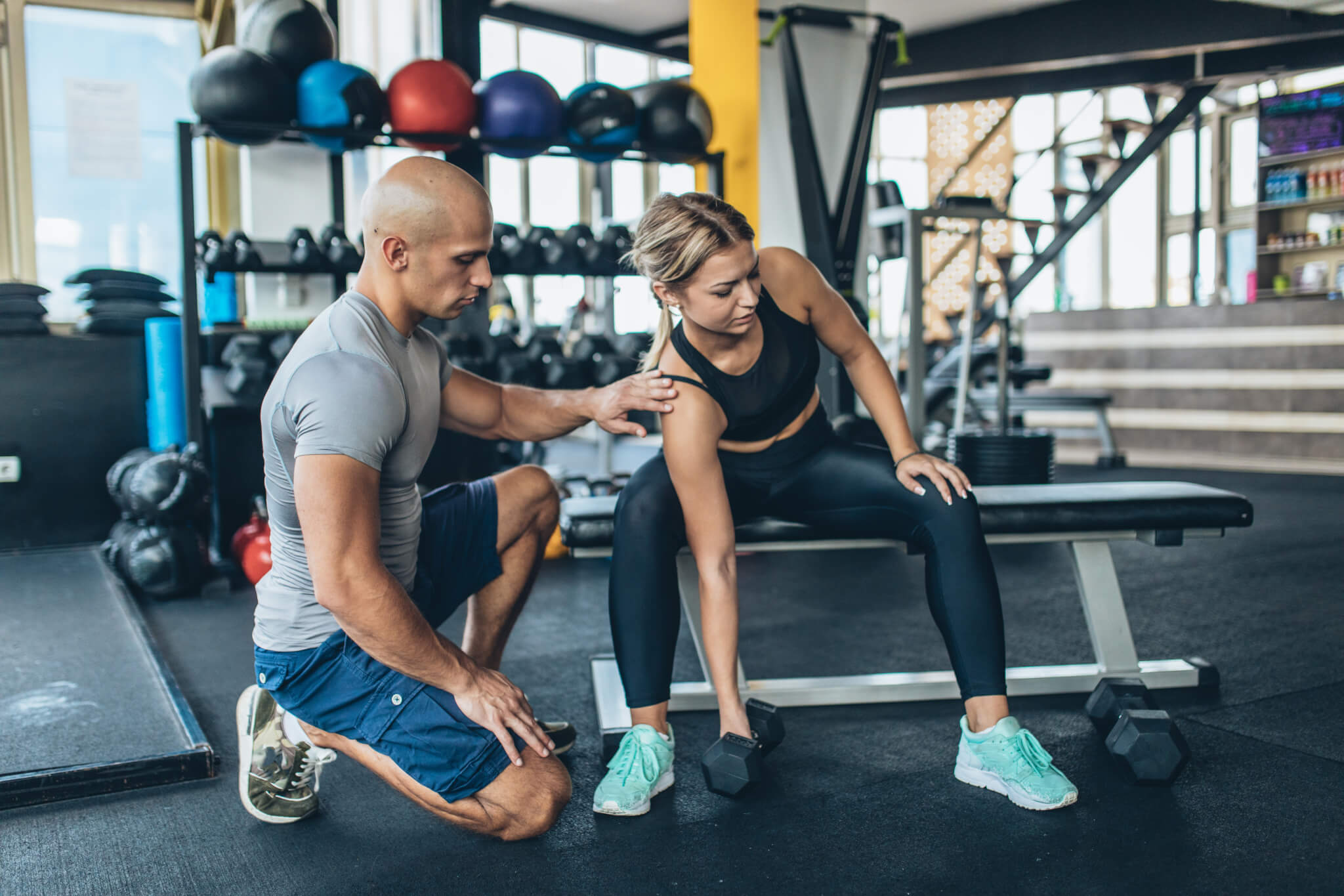 Fitness trainer teaching girl weightlifting